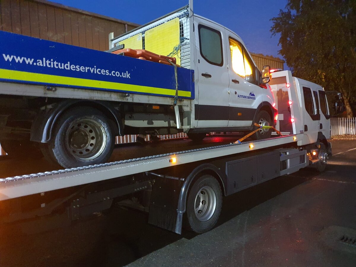 Breakdown Man recovering an Altitude Services Ford Transit dropside van on the recovery truck at night.