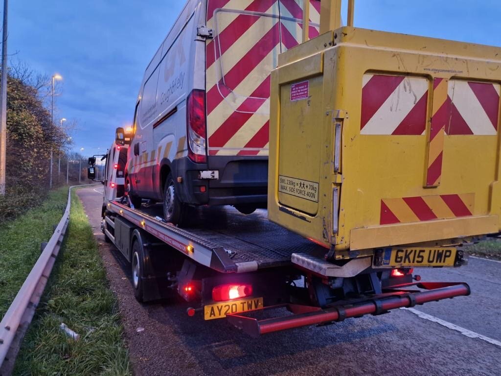 Cough & Kelly cherry-picker Iveco van AY20 TWV loaded on Breakdown Man's recovery truck at dawn.
