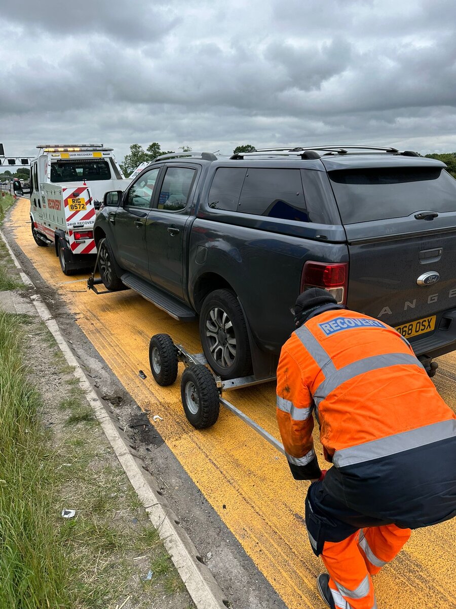 Black Ford Ranger pickup loaded on Breakdown Man's recovery truck, strapped down on the hard shoulder.