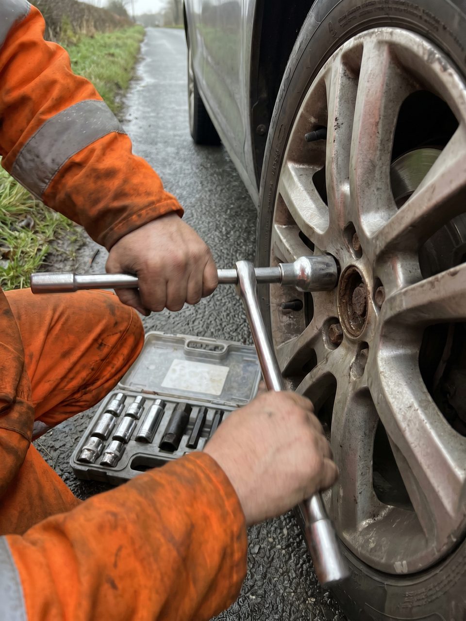 A stubborn locking wheel nut being removed from a car's alloy wheel with a specialist extraction socket.
